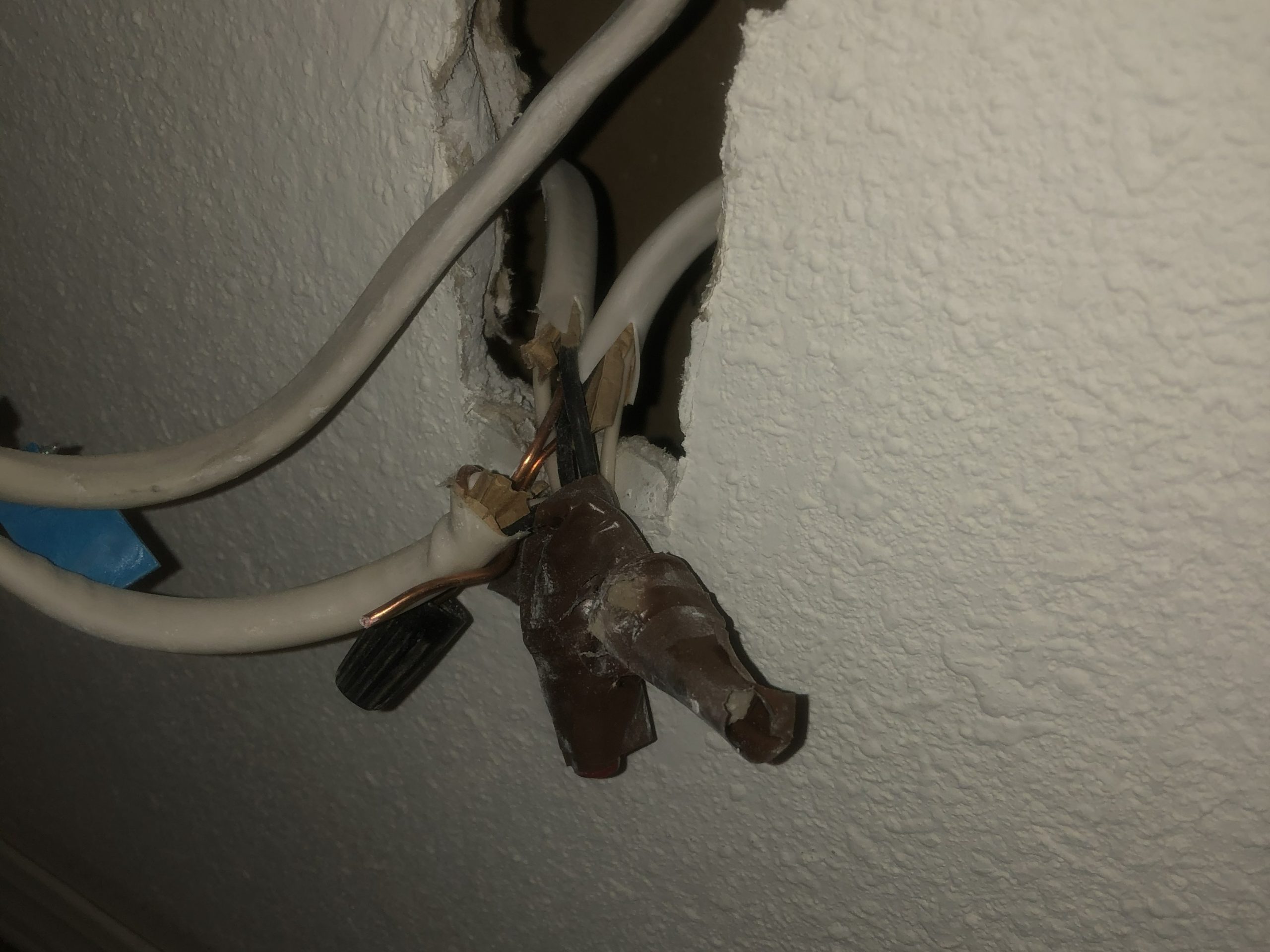 Exposed residential electrical wiring behind a wall before repair