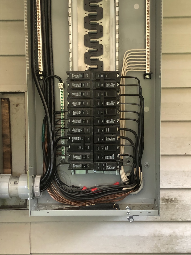 Older exterior electrical panel with crowded wiring before upgrade planning