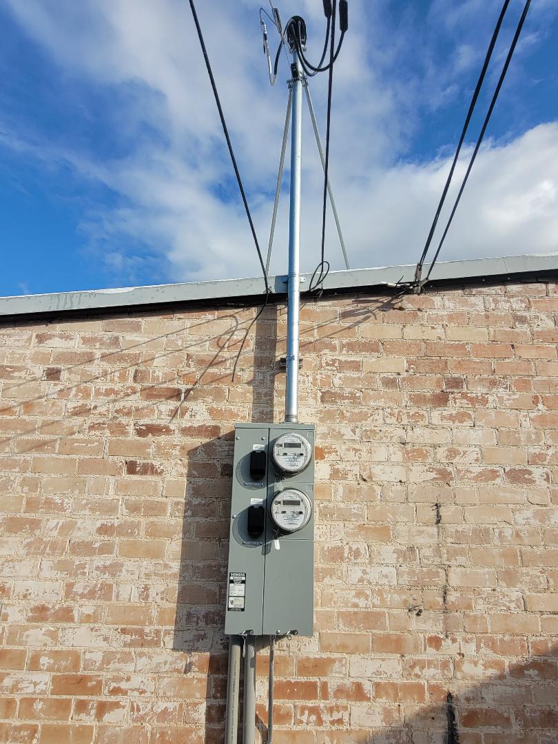 Residential overhead electrical service with exterior panel, meter location, and service mast
